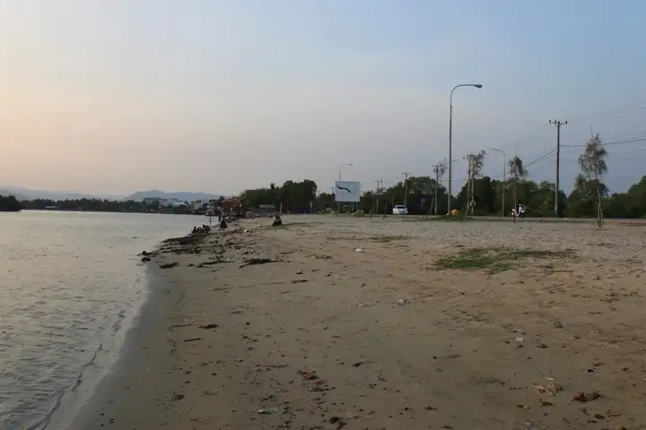 Sandy shoreline and riverside buildings at Kampot River Beach